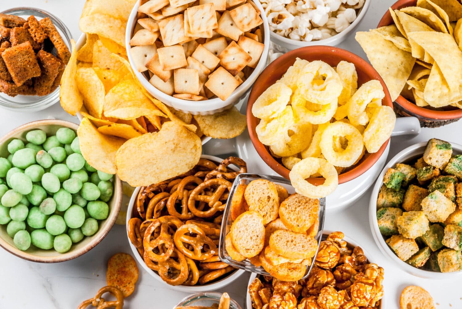 An assortment of snacks including chips, nuts, and cookies on a table.